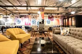 The interior lounge of a co-working space on Deskpass. It includes desks, chairs and a large couch.