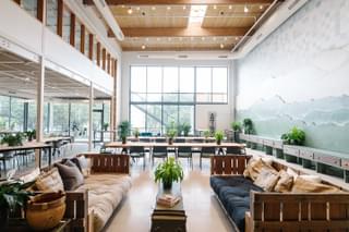 An interior shot of a coworking space lounge with expensive ceilings and plenty of couches and desks.