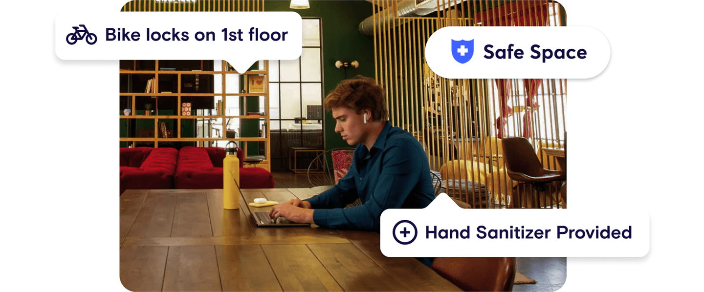 A person sitting at a coworking desk, browsing options for safety for a coworking space in the Deskpass app.